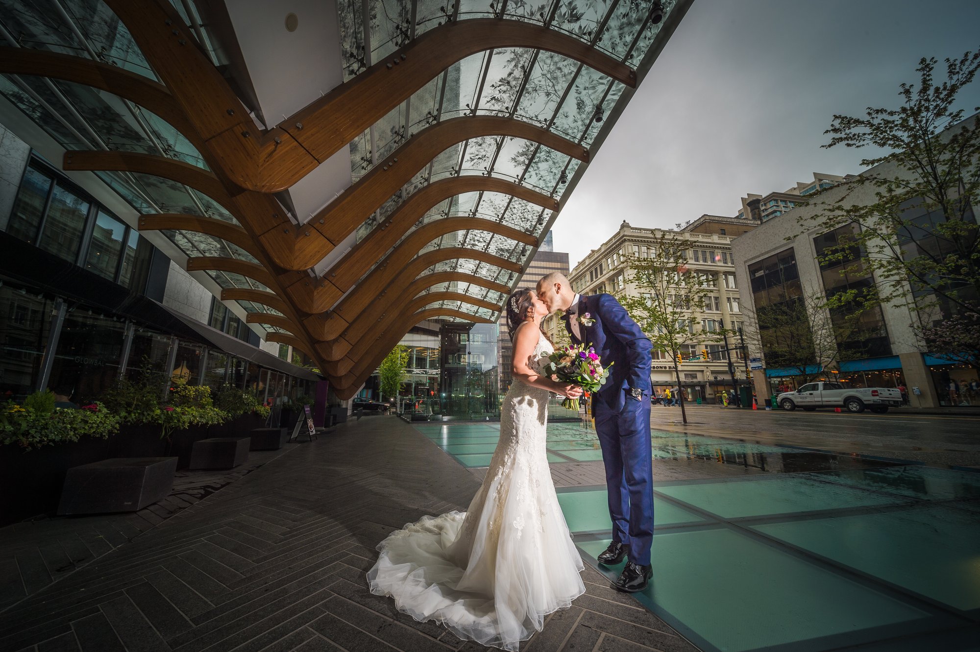 Ozzy and Jessica kissing under a white umbrella in the rain in Vancouver